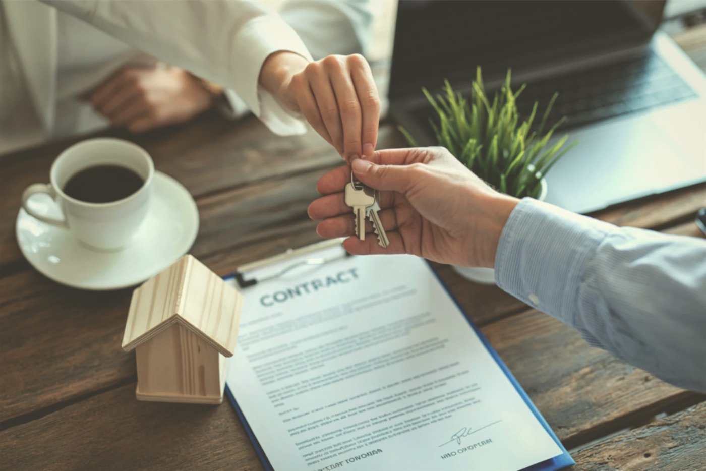 Keys handed across a desk beside a lease and a model house